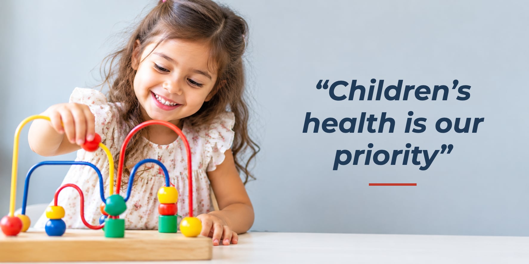 A smiling girl playing with a toy, with the words: Children's health is our priority